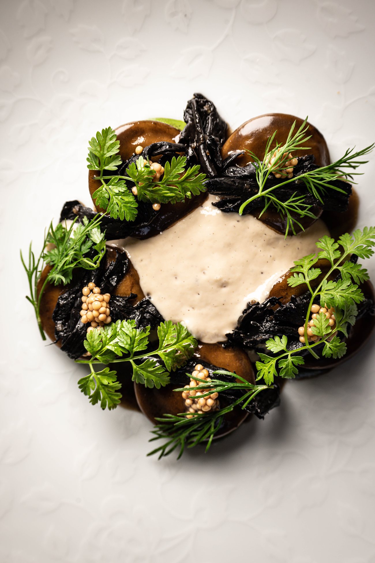 Une entrée de Substance : champignons, herbes et émulsion sur assiette blanche